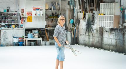 Scenic Artist, Ali Allen, stood on a large white fabric cloth ready to paint a new backdrop