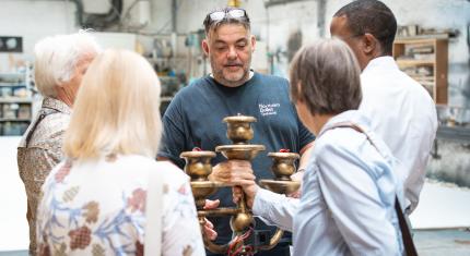The Northern Ballet Technical Director showing one of the props, a gold coloured candelabra, to four donors