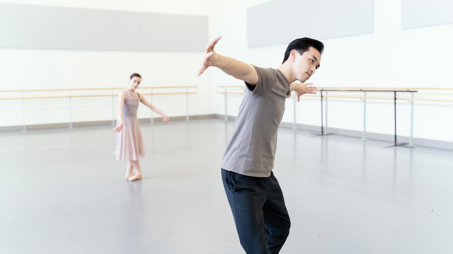 One dancer in the background follows the movements of another in the foreground