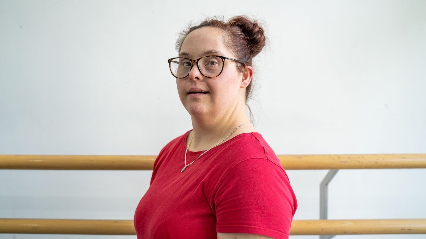 Woman with brown hair tied up, glasses and a red T-shirt