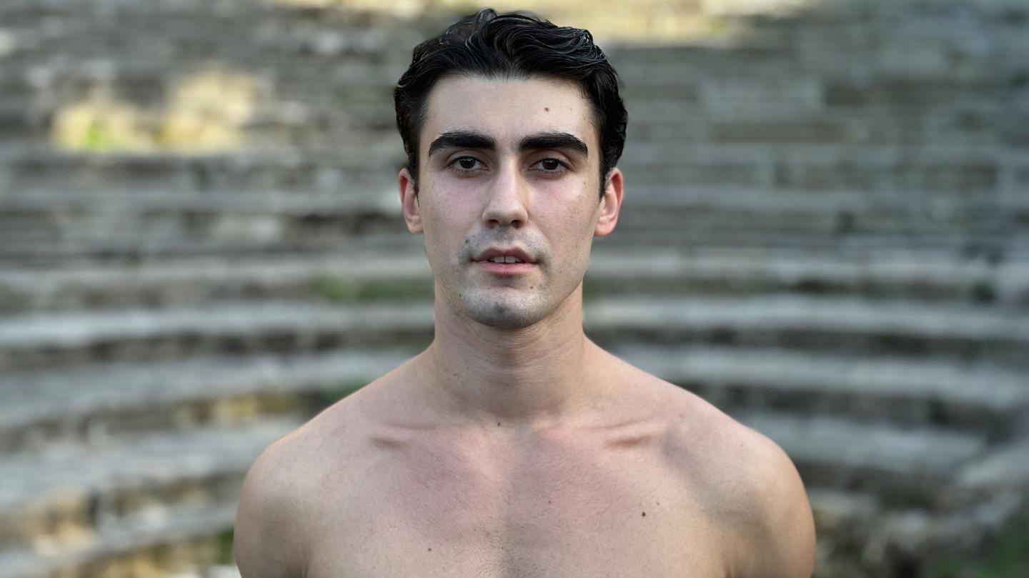 Male dancer, shirtless, dark hair, looking directly at the camera