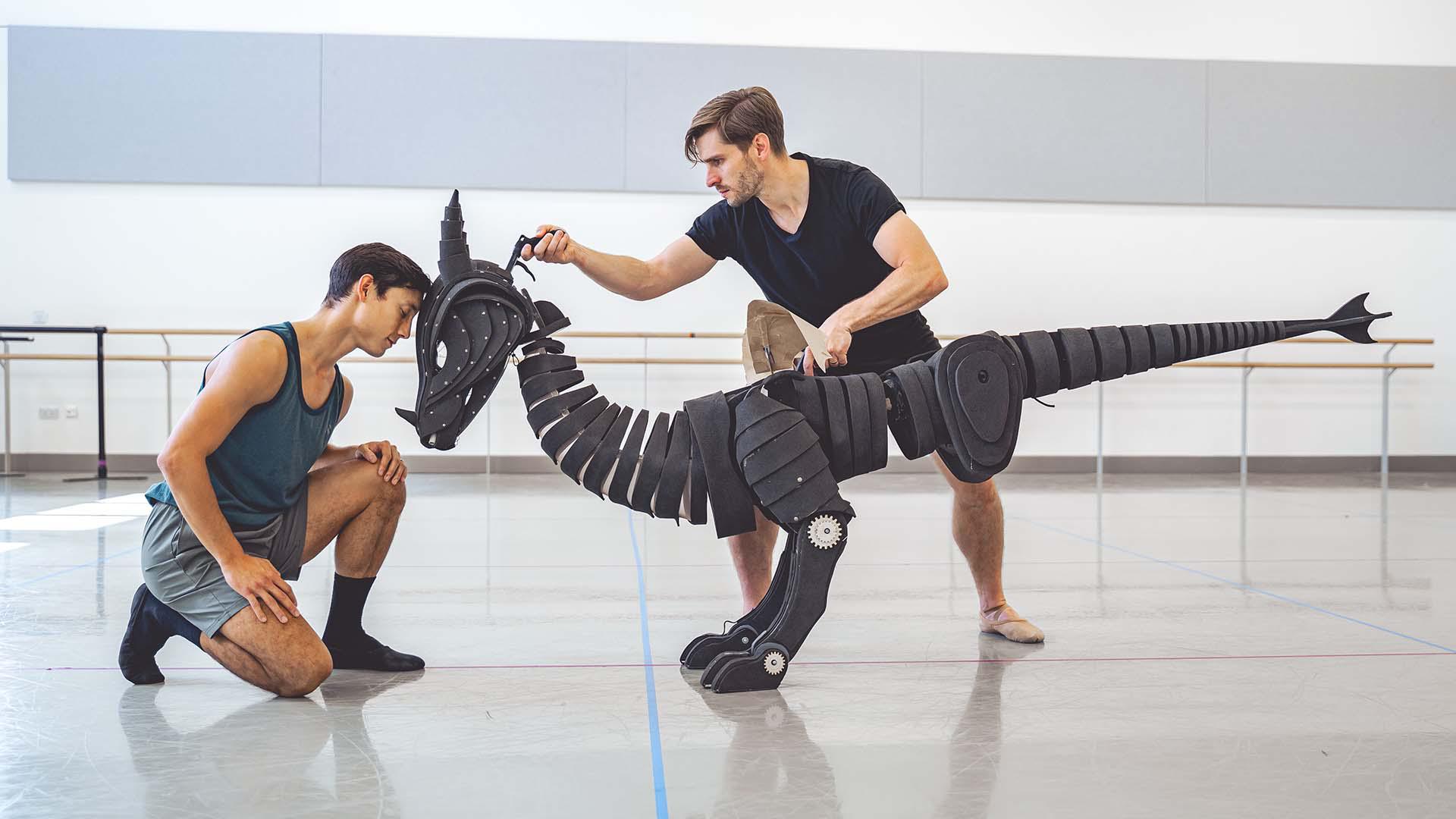 A dancer rests his forehead against a dragon puppet's forehead, the dragon puppet controlled by a second dancer