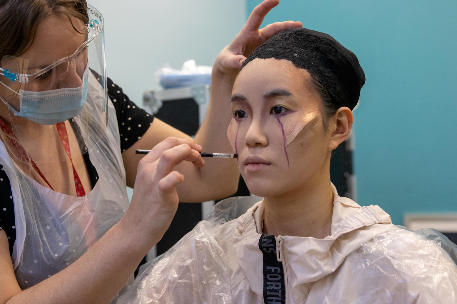 Make up artist applies face paint to a female dancer