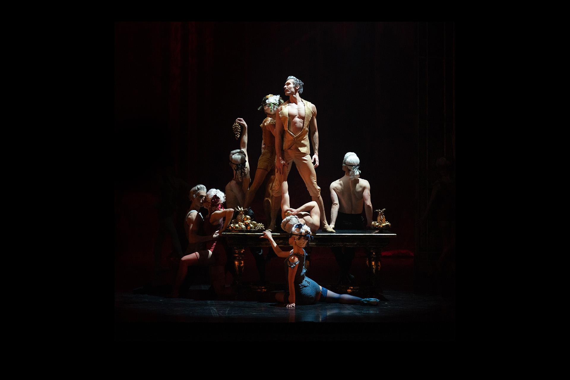 Casanova stands on a table proudly surrounded by people half-dressed