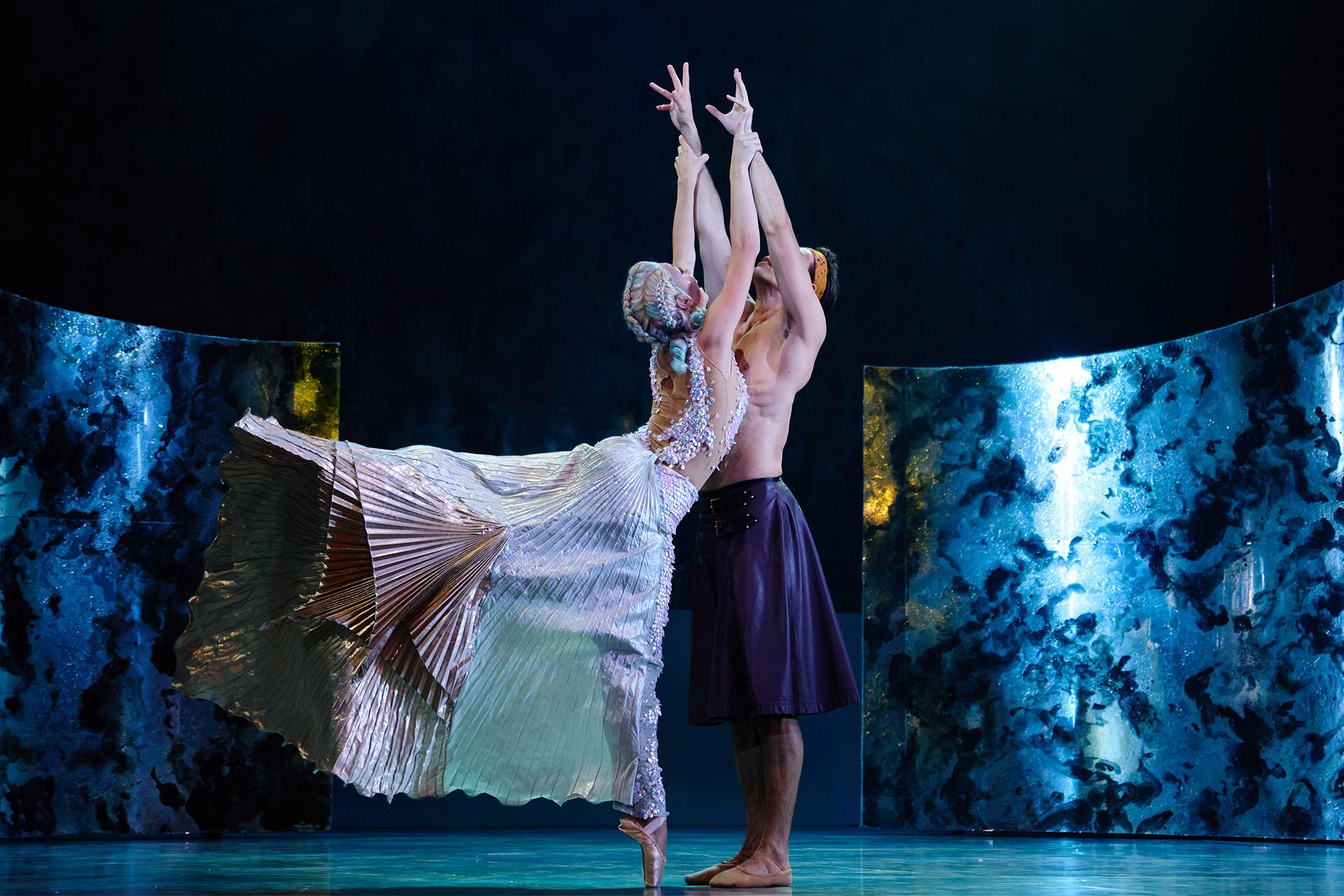 The Little Mermaid, production, 2022, Abigail Prudames and Joseph Taylor. Photo Kyle Baines Man reaching up while a female mermaid with tail flowing behind her holds his wrists