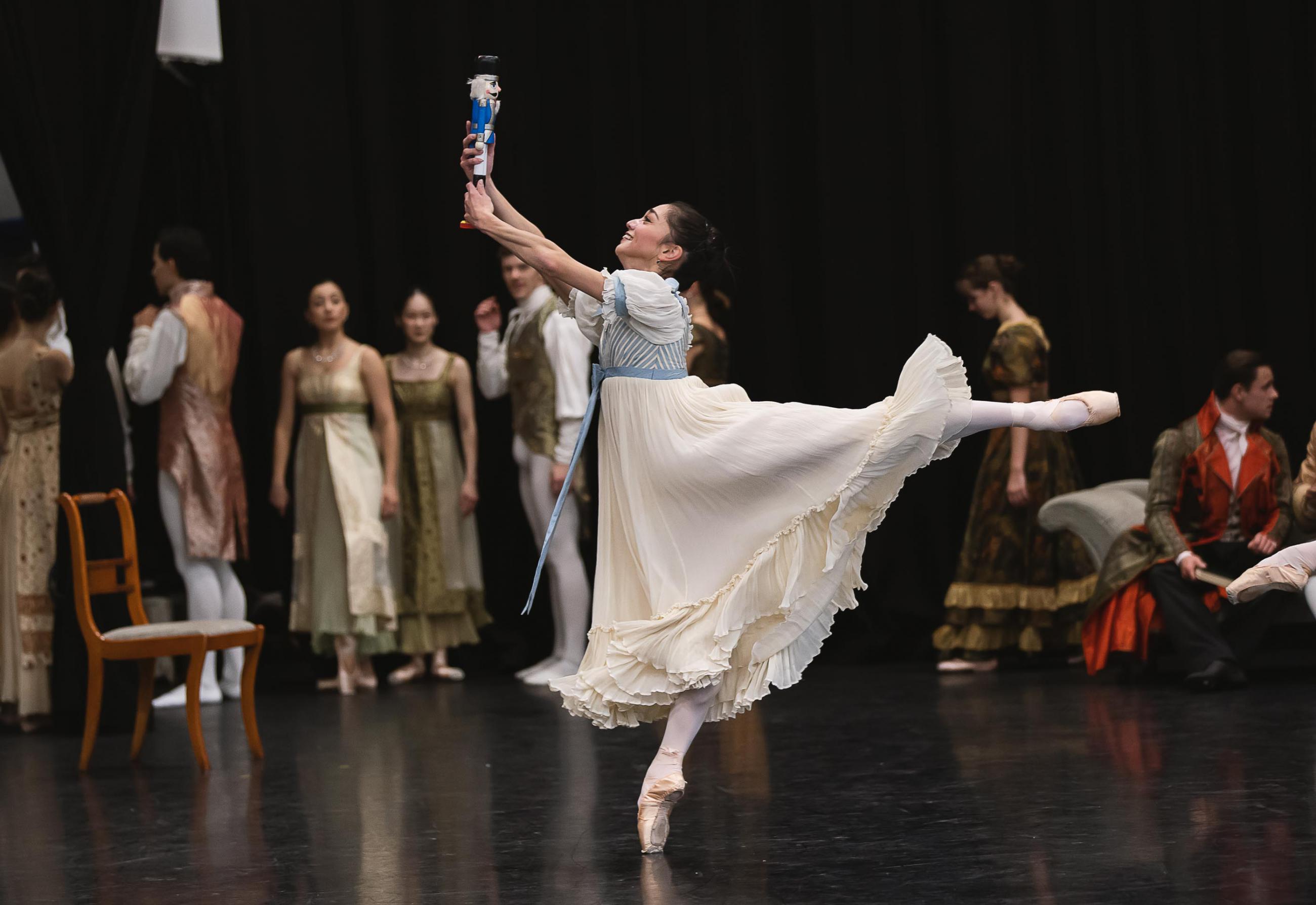 A dancer in arabesque holding a Nutcracker doll