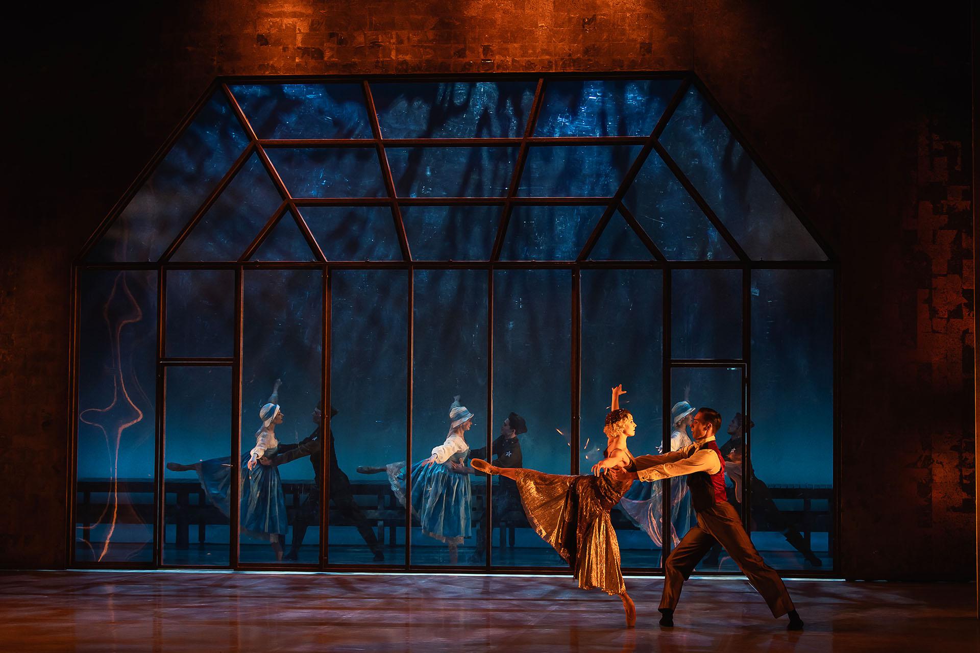 Under a warm light two lovers dance while in the background their former selves mirror their movements