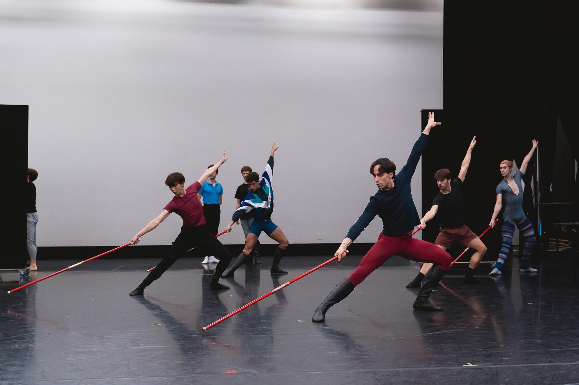 A group of male dancers with staffs on the floor