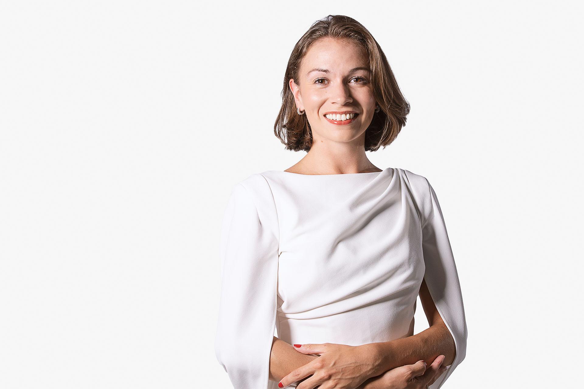 Woman with dark hair in a bob wearing a white top smiling broadly