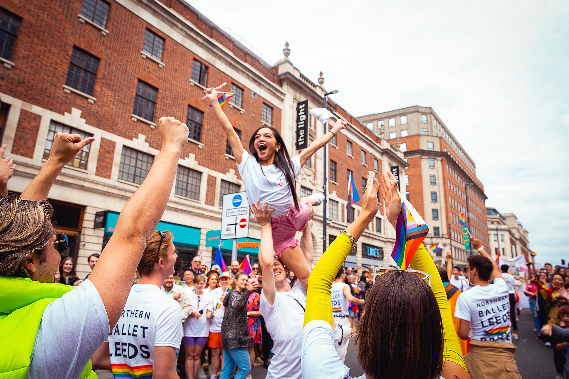 Laughing woman with long dark hair lifted by overhead with her arms raised in celebration