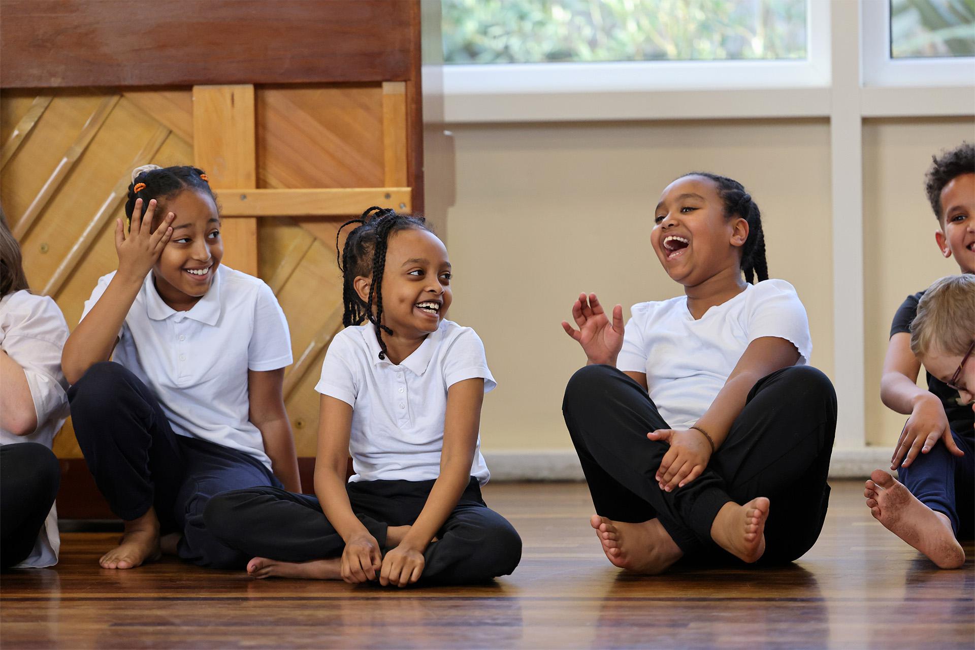 Three girls sat on the floor cross-legged, laughing