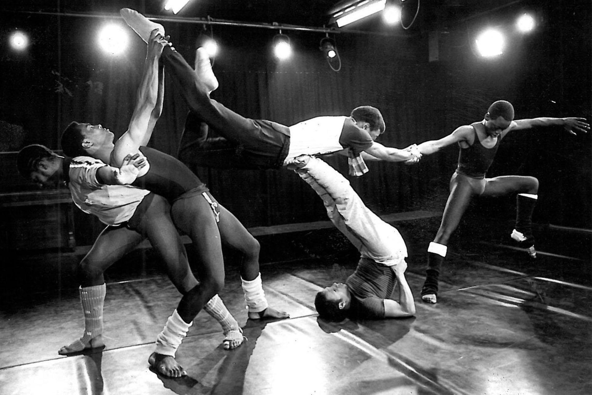 SABT - Phoenix - Midnight 1983, Photo Terry Cryer Monochrome image of five black people dancing, supporting each other, one lifting another while laying down, another leaning, one providing balance by holding and pulling