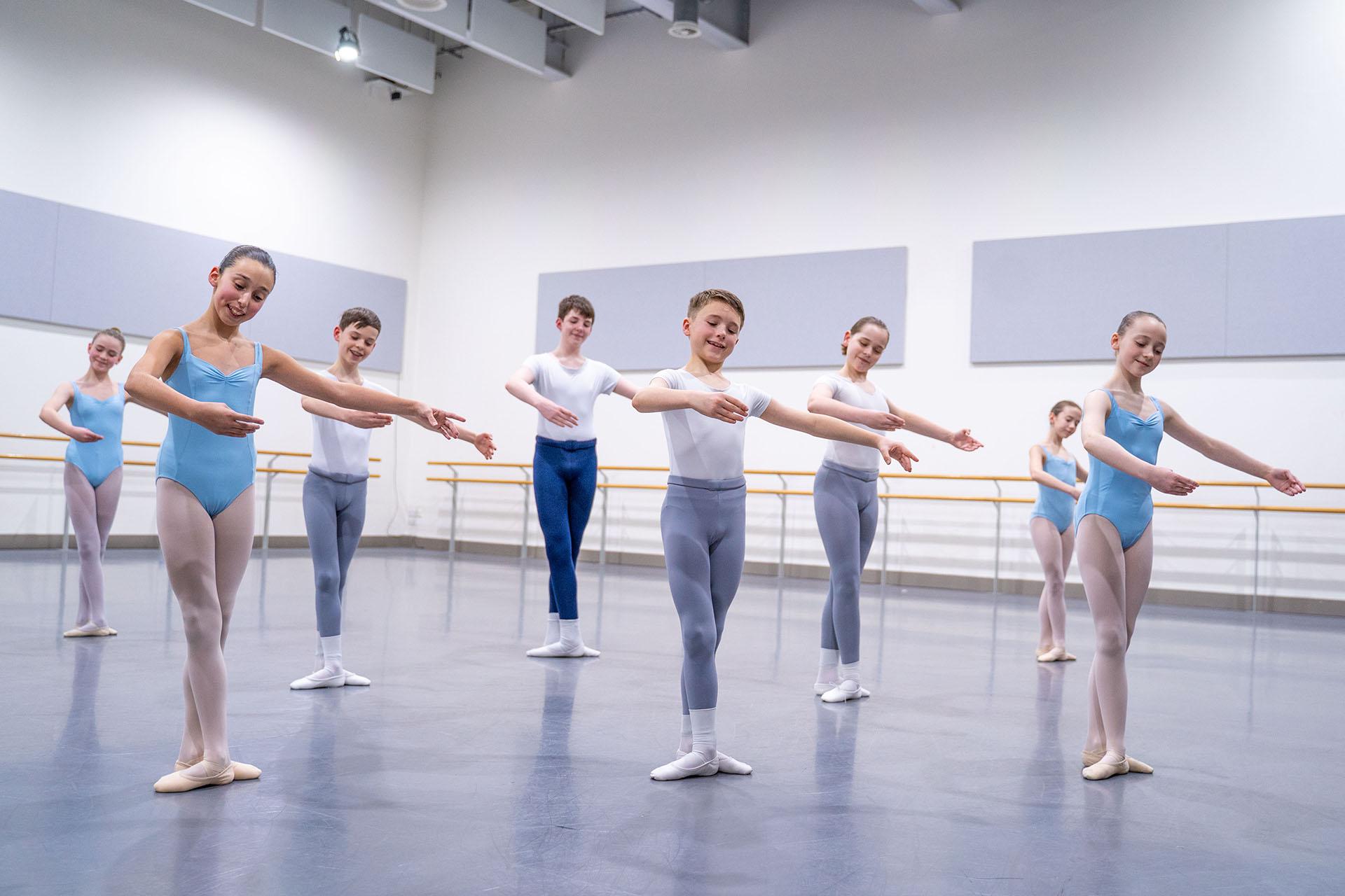 Eight children, mixed genders, holding a similar pose and smiling as they take part in a class