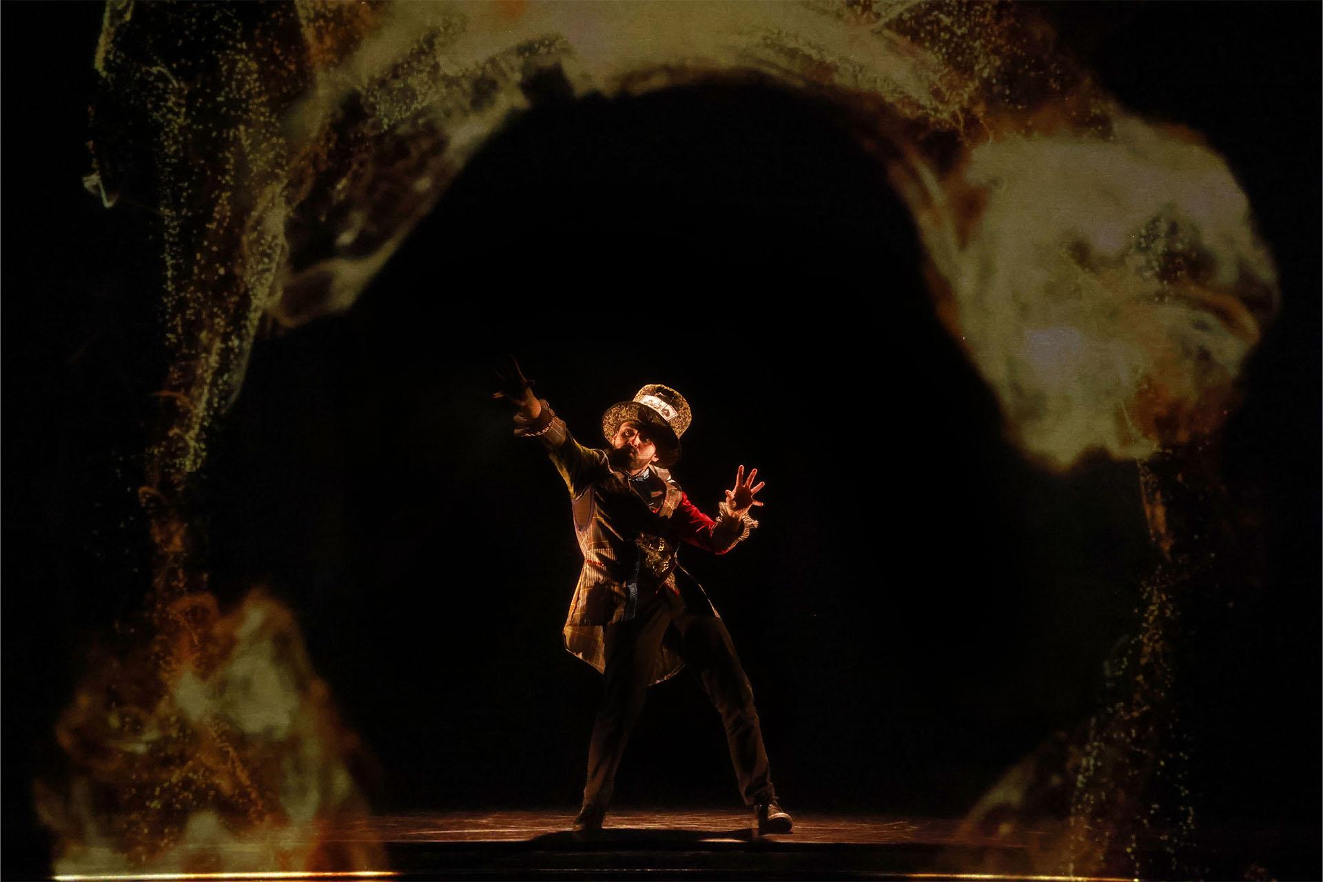 A man in a large top hat waves his arms and a swirl appears in front of him