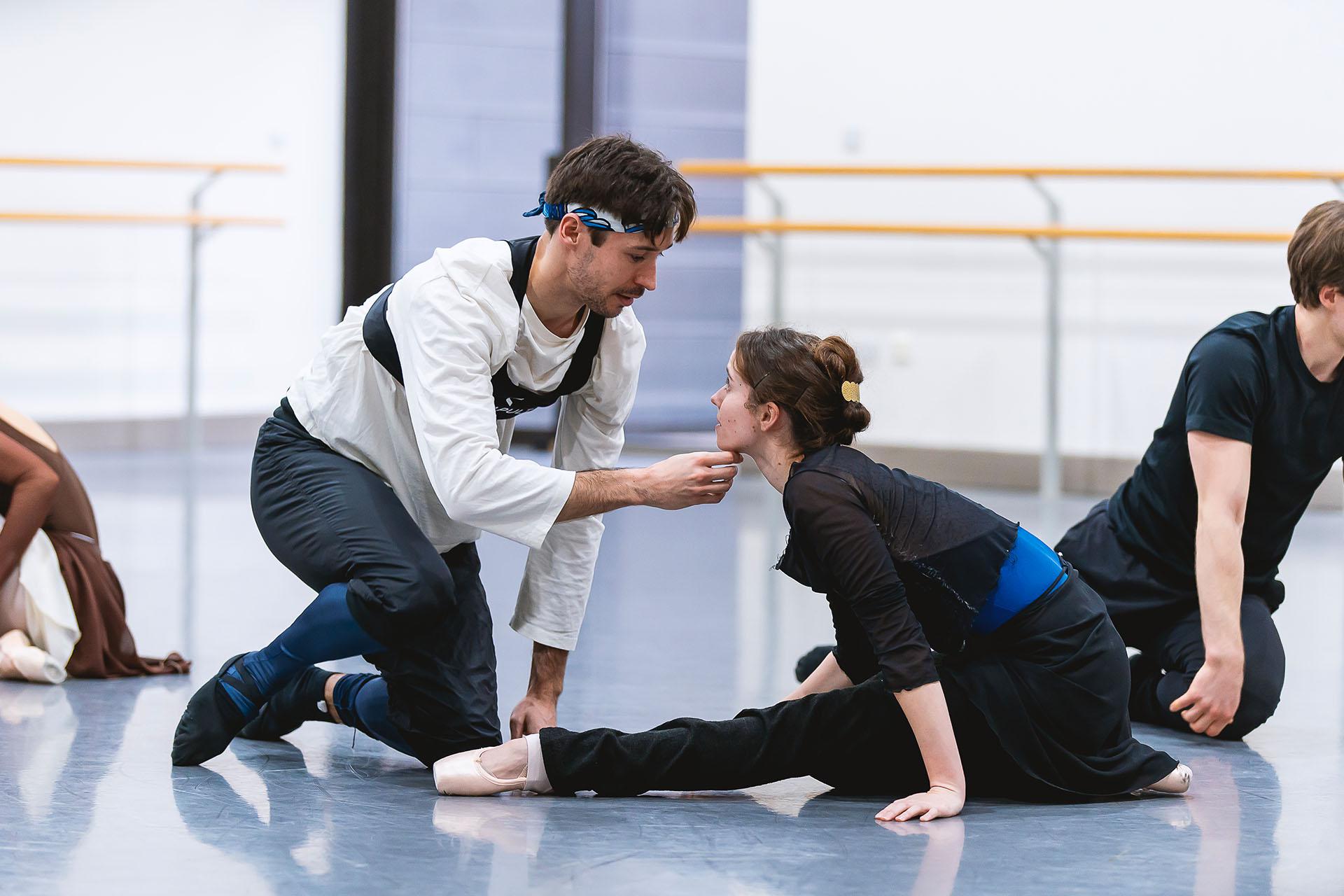 Two dancers rehearsing, on holds his hand under her chin raising her eyeline to meet his