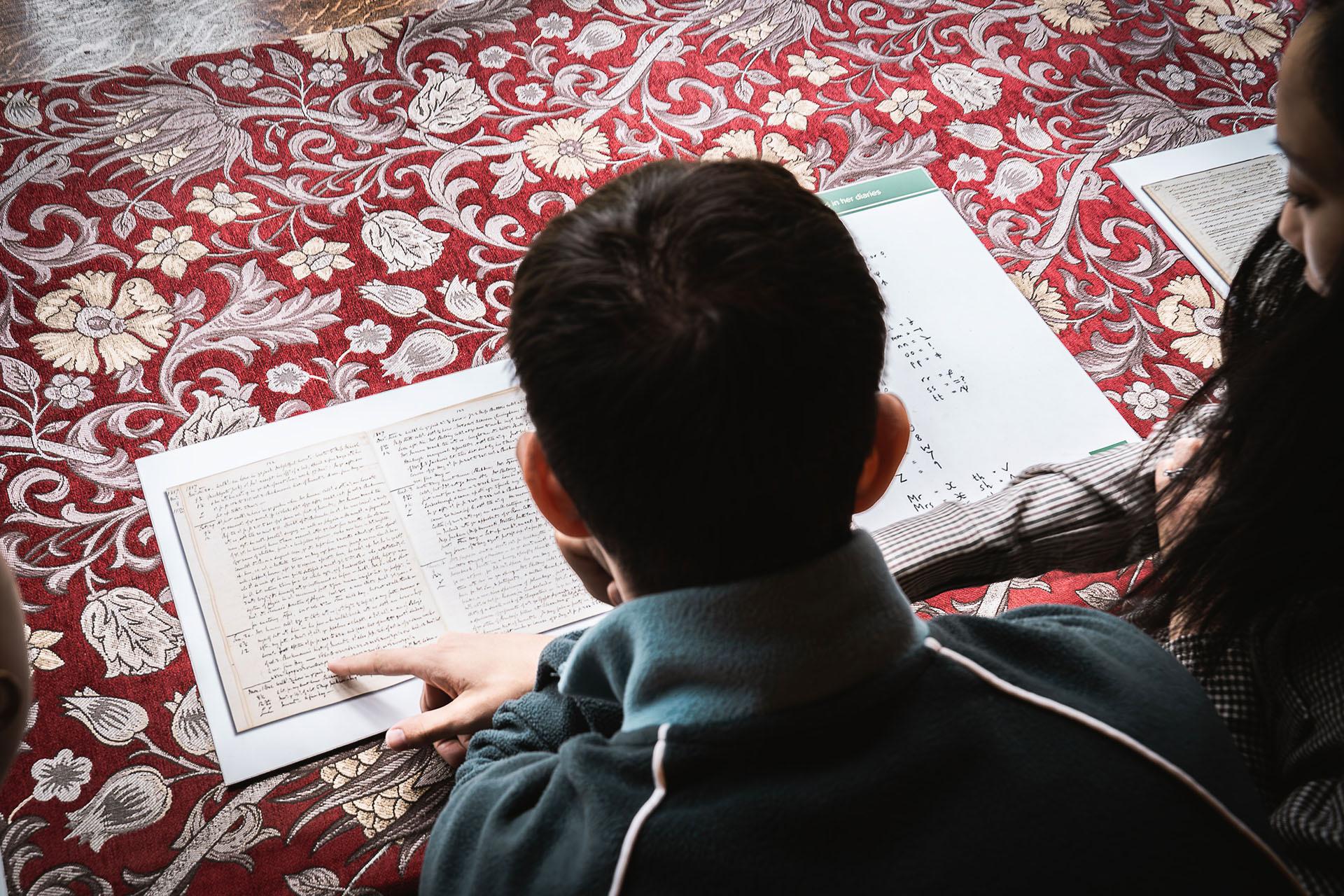 Laid upon an ornate fabric, Northern Ballet dancer Albert González Orts examines one of Anne Lister's diaries.