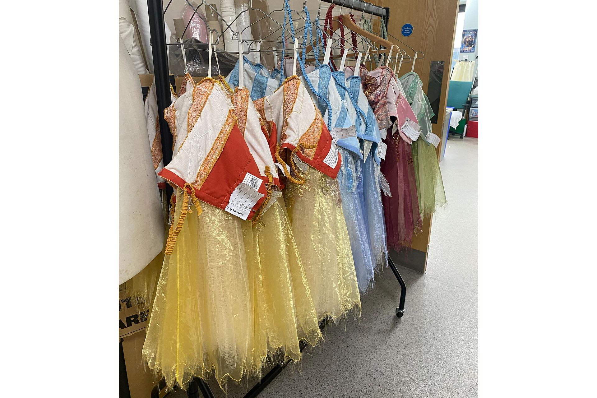 A clothes rail in Wardrobe filled with gold and blue dresses to be used in the production of Cinderella