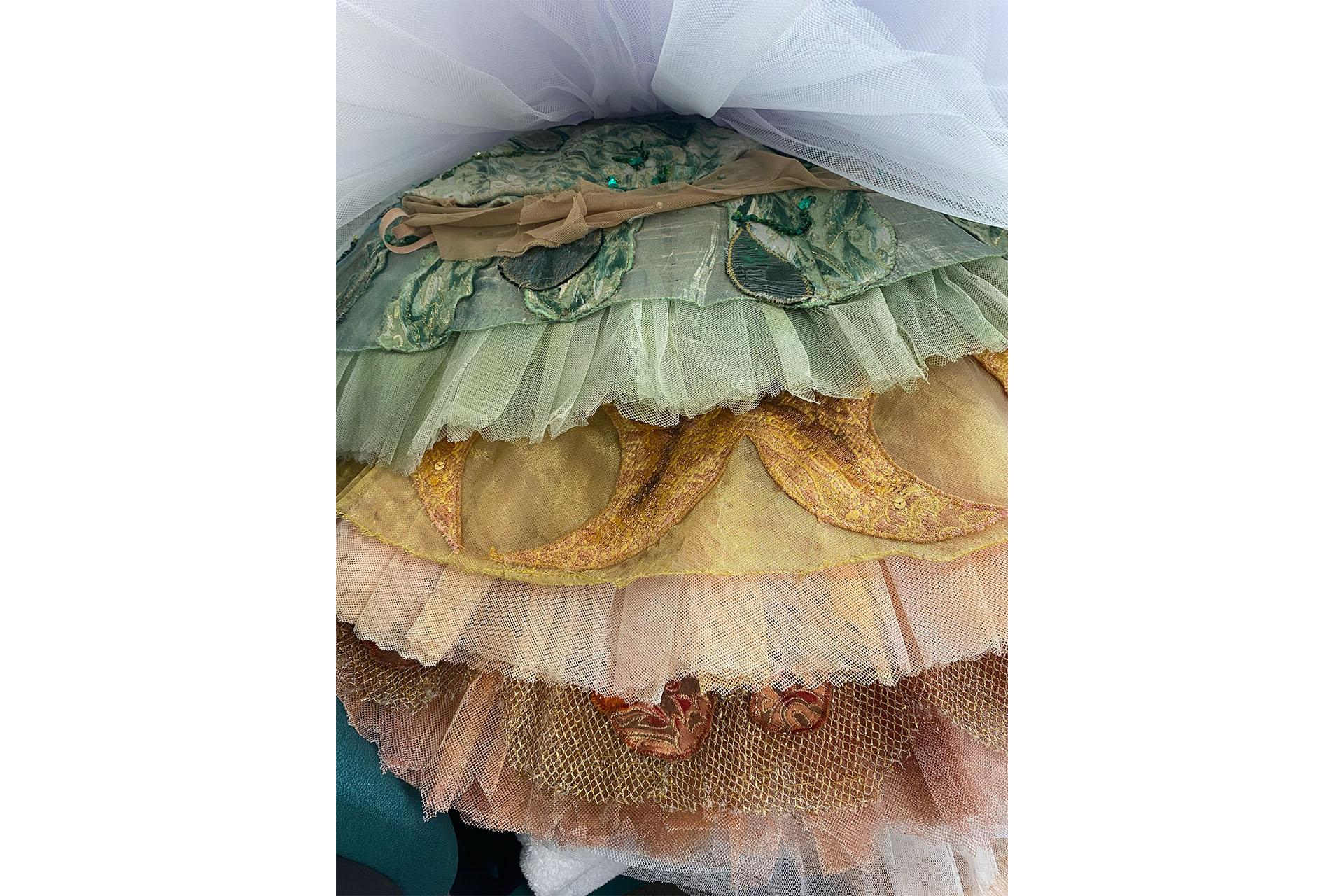 A close up of a vertical stack of tutus, orange, gold, green and white