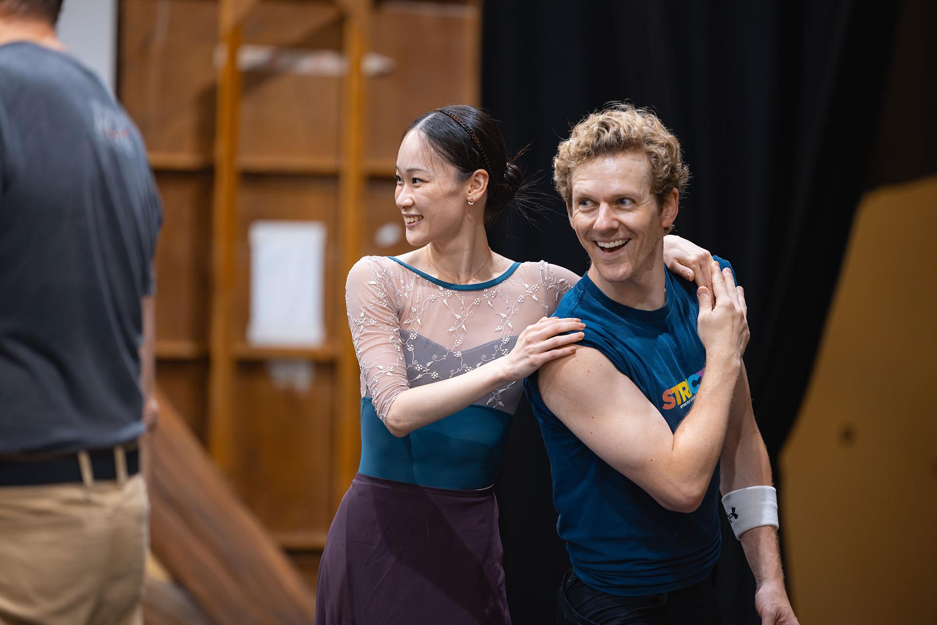 Two dancer in rehearsal smiling at something happening beyond the frame