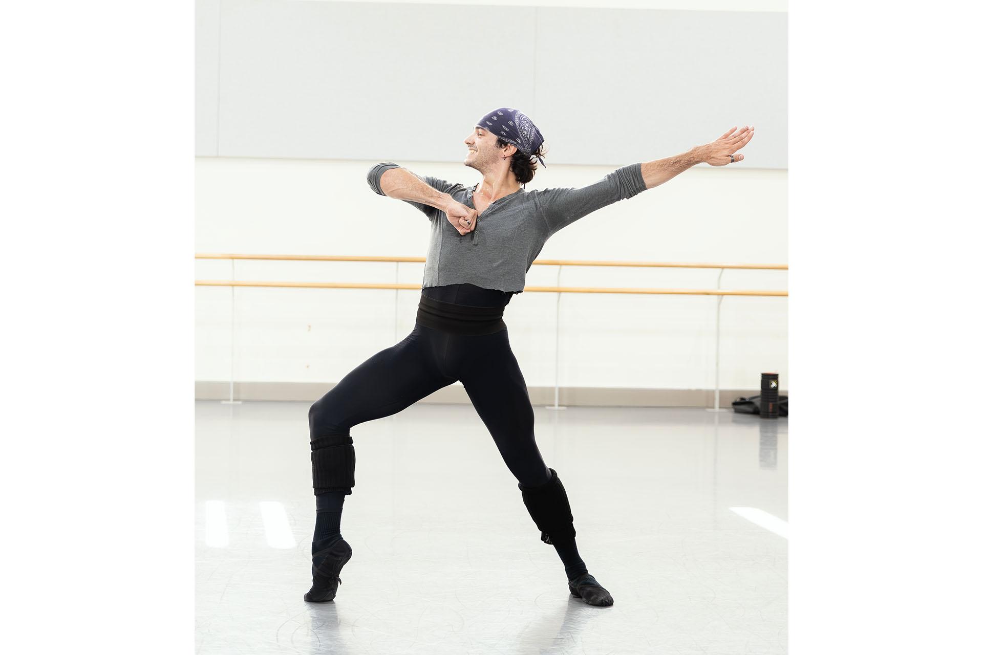 Dancer in a bandana, grey shirt and black trousers in a pose straight from Tango
