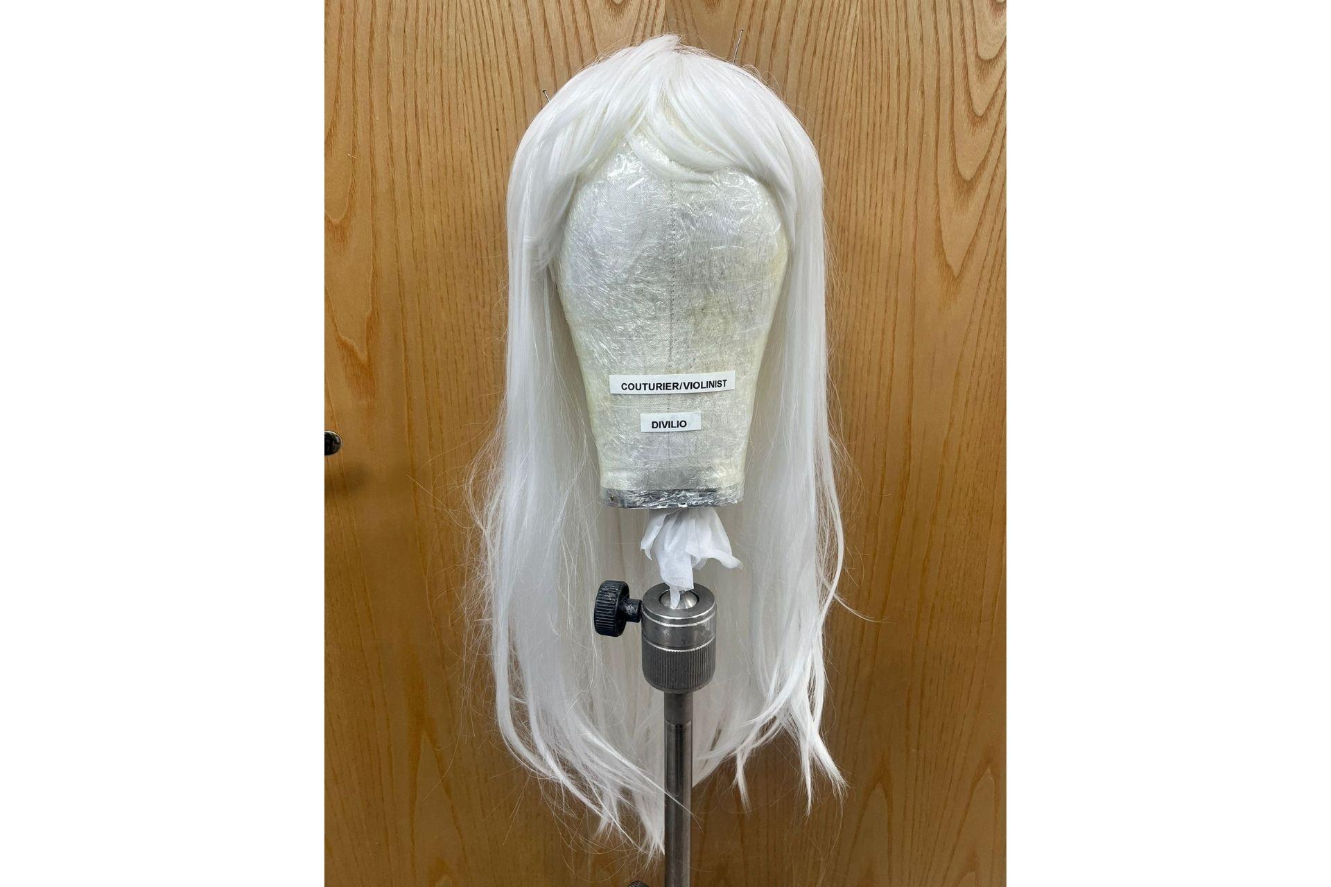 A long wig with straight white hair sits on a mannequin head