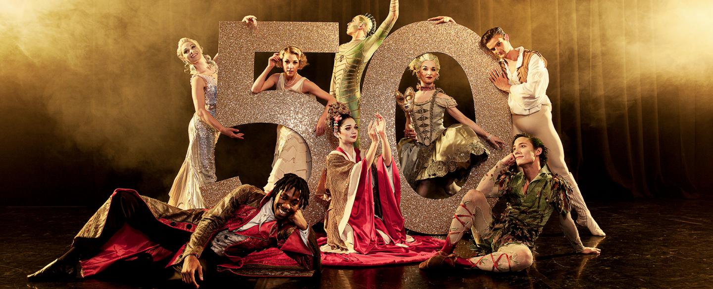 Northern Ballet dancers posing in front of a large number 50 wearing costumes of different productions. Photo Guy Farrow.
