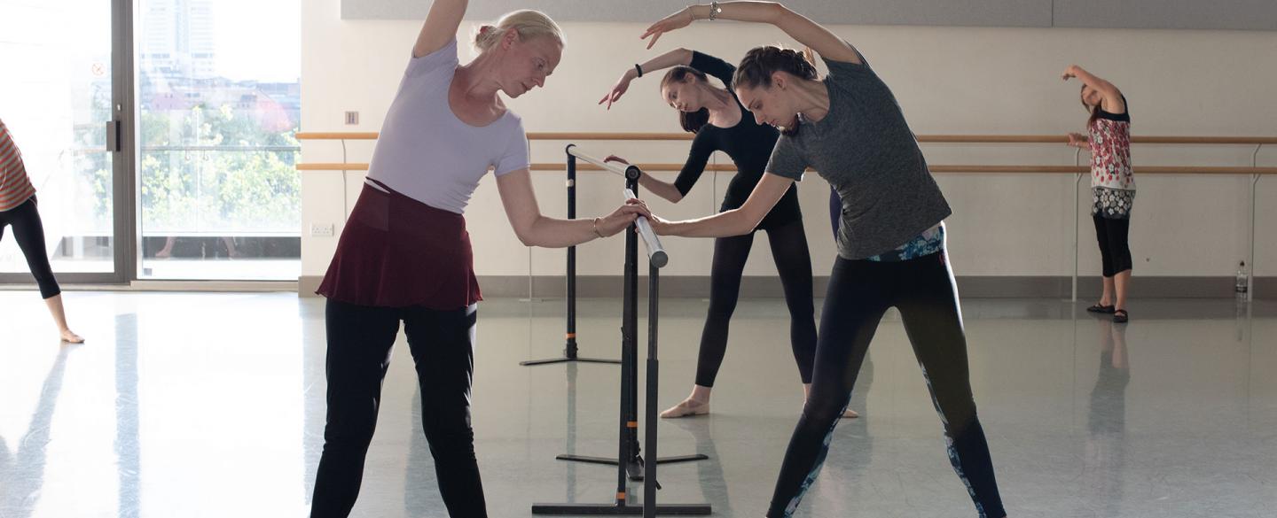 Dancers stretching at the barre in the Academy's adult class. Photo Kathie Tiffany.