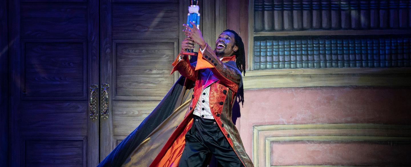 Uncle Drosselmeyer holds the toy nutcracker high