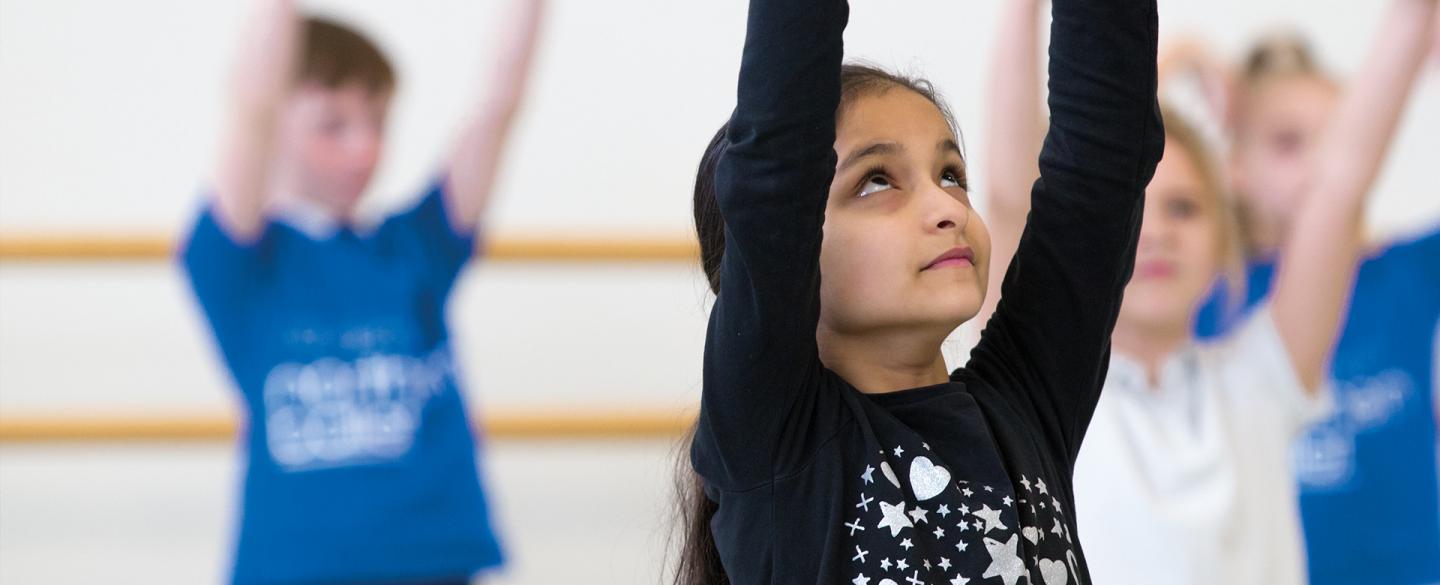 A class of children raise their hands in the air