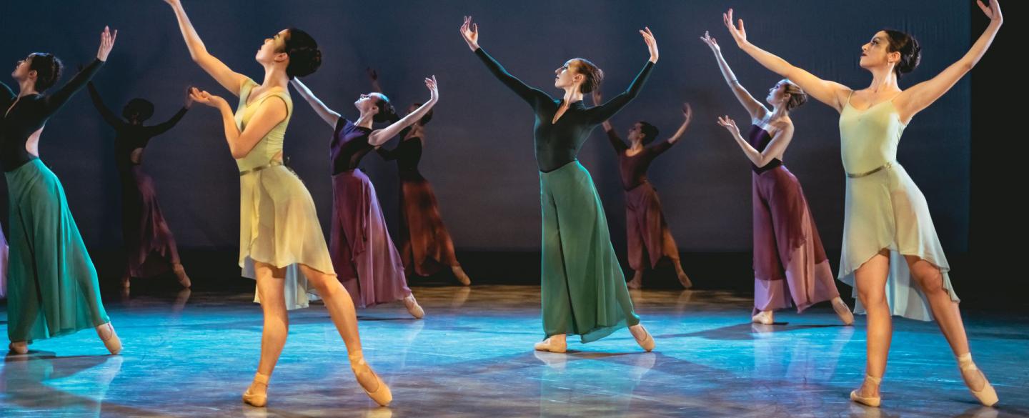 A group of dancers on stage in yellow, blue and green outfits