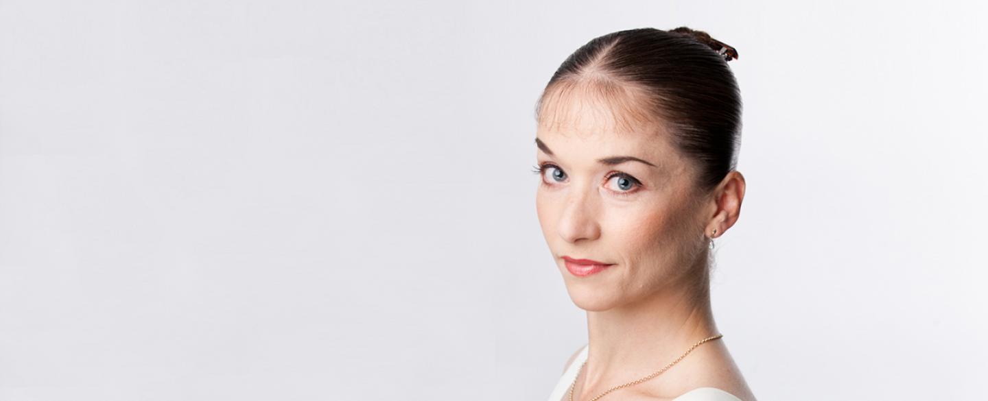 Pippa Moore is standing side on to the camera, with her head turned to face the camera.