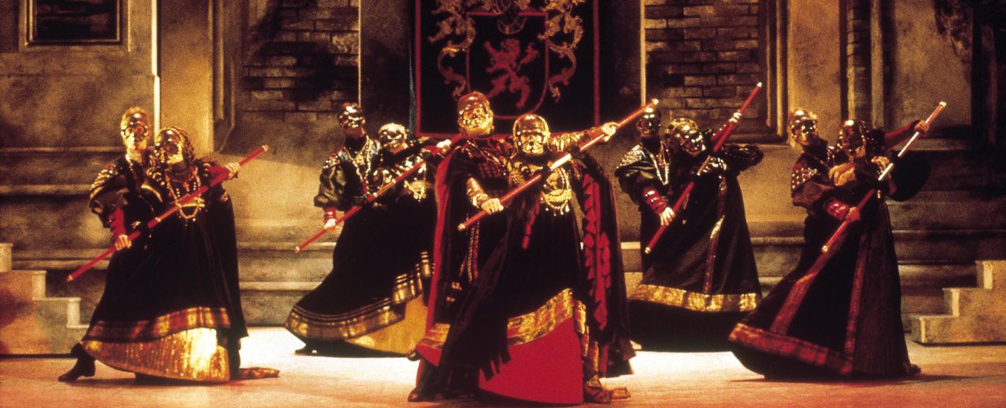 A group of dancers in heavy, dark Italian costumes perform with swords.