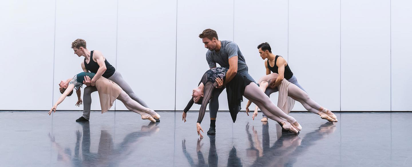 Three male/female couples him supporting her by the waist as she as she leans back, draped over his hold and en pointe.
