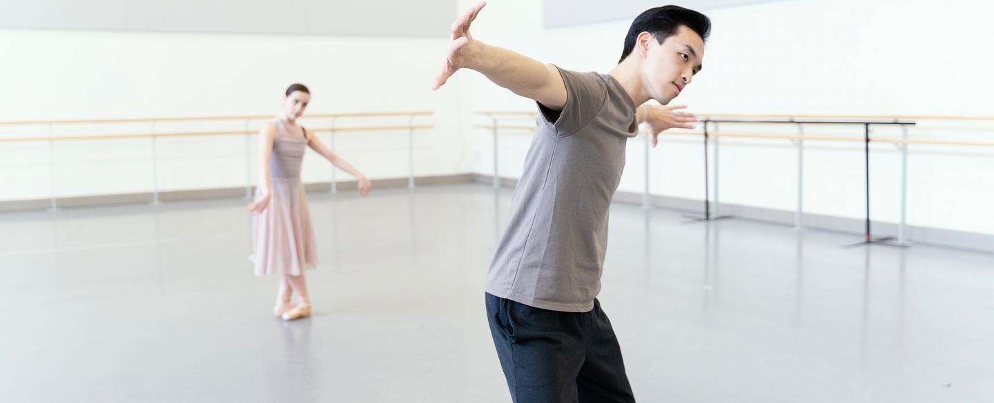 One dancer in the background follows the movements of another in the foreground