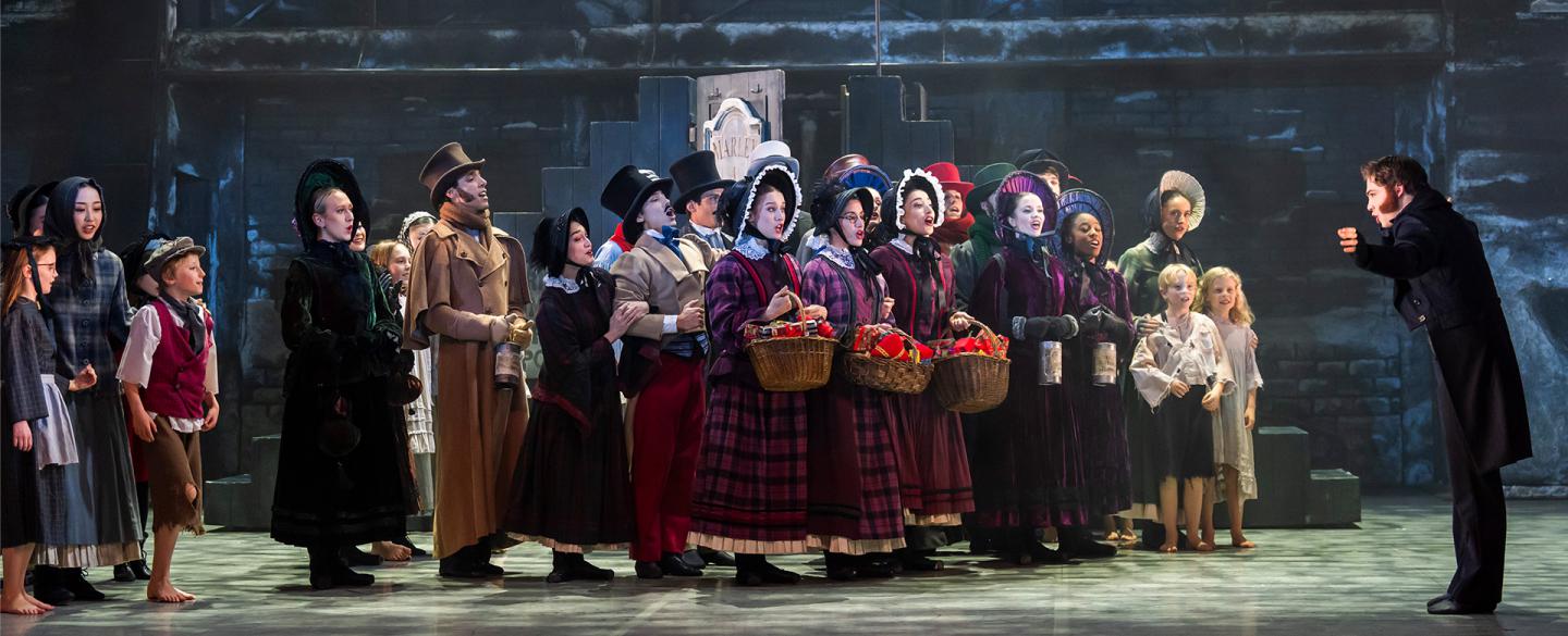 A photo of a group of dancers singing in Victorian era clothing