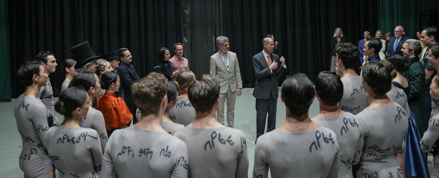 Northern Ballet dancers in a circle on stage meeting HRH The Duke of Edinburgh