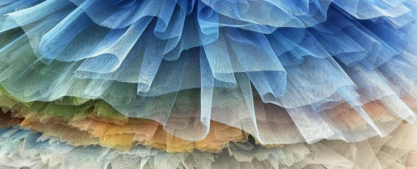 A vertical stack of tutus ranging from white to blue