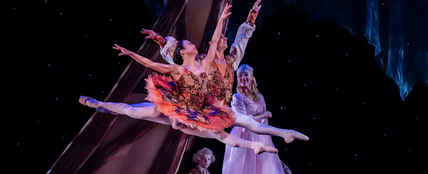 Leaping across the stage, dancers in their tutus, wearing poite shores and looking up