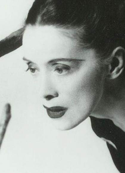 Monochrome image of a woman with bold lipstick leaning forward, her dark hair is tied back and she seems to have rope around her shoulders