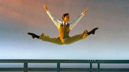 Kevin Poeung as Nick Carraway leaping with his legs in splits in The Great Gatsby. Photo Emma Kauldhar