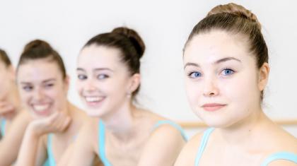 1 dancer looks into the camera as three dancers look on smiling