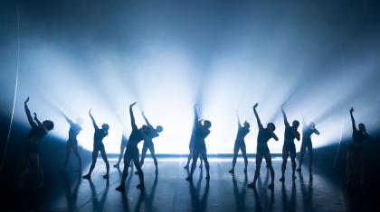 A group of dancers with intense lighting behind