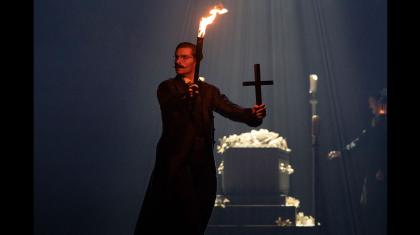 Van Helsing holds a torch in one hand and a crucifix in the other as he explores the tomb