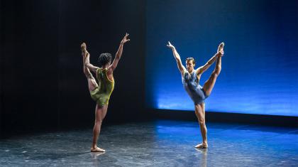 Mlindi Kulashe and Andrew Tomlinson face each other as they reach high with one arm whole holding their left leg aloft with the other
