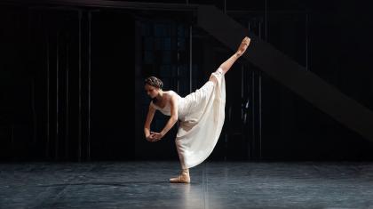 Victoria leans forward and raise a leg high behind her