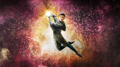 Dancer leaps holding light in his hands.