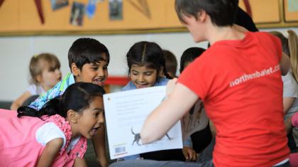Children are excited at the contents of a book being shown to them by a Dance Education Officer