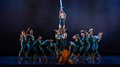 The Lady of the Lake, surrounded by water, holds the fabled Excalibur high above her