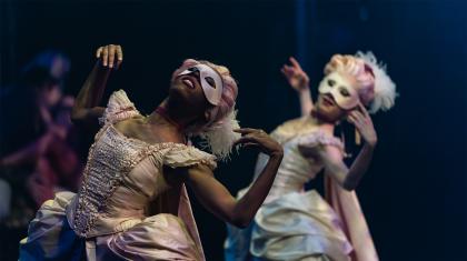 Female dancers wearing masks and 18th century costumes