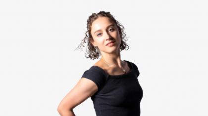 Headshot of female dancer in a black top with short curly hair